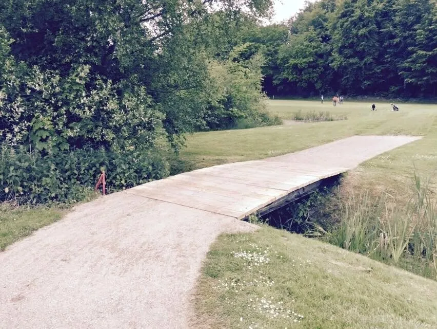Håndbygget naturbro i træ over et vandløb på Helsingør Golfklubs bane