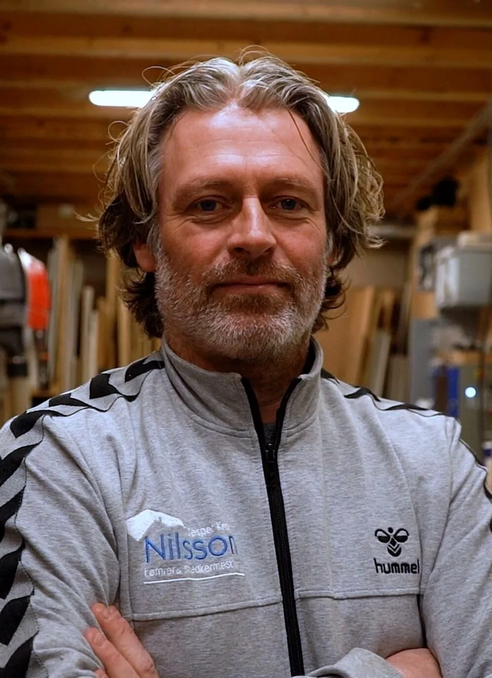 Jesper Krogh Nilsson i sit værksted med træ og maskiner bag sig