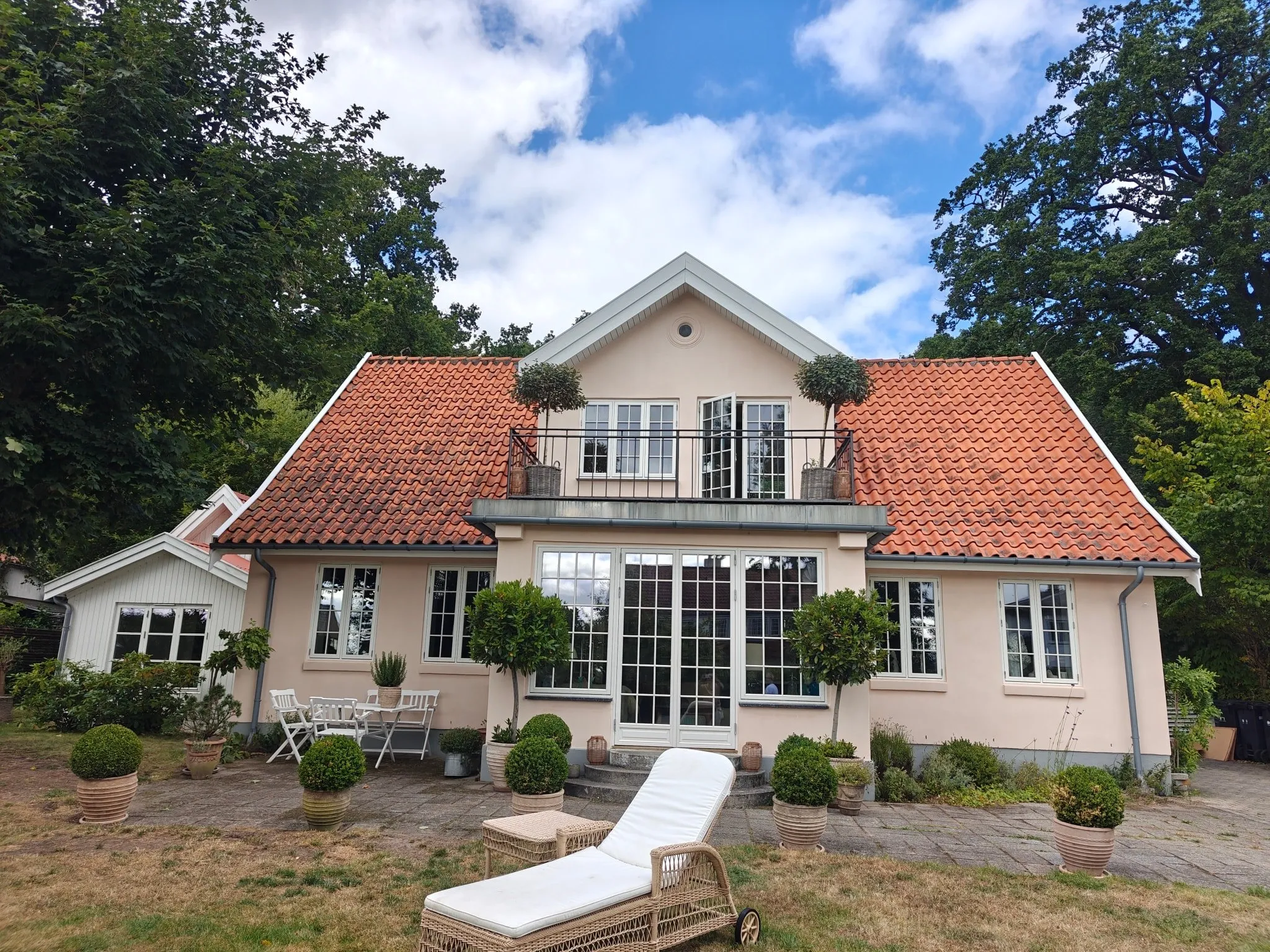 Villa med nymalet lys facade, hvide vinduer og rødt tegltag