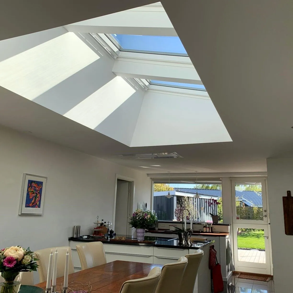 Spisekøkken med stort ovenlysparti og sol gennem Velux-vinduer